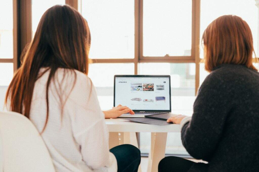 Descubra a nossa curadoria: Vendas online, crescimento no mobile, ferramentas e aplicativos 1 two women talking while looking at laptop computer