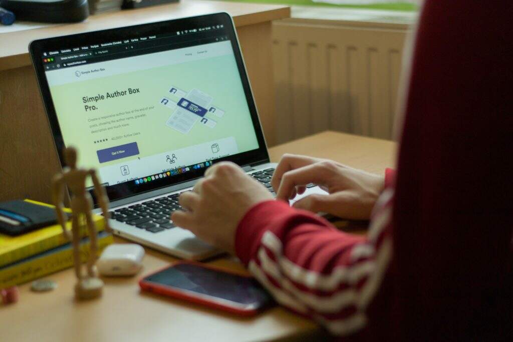 person using macbook pro on brown wooden table