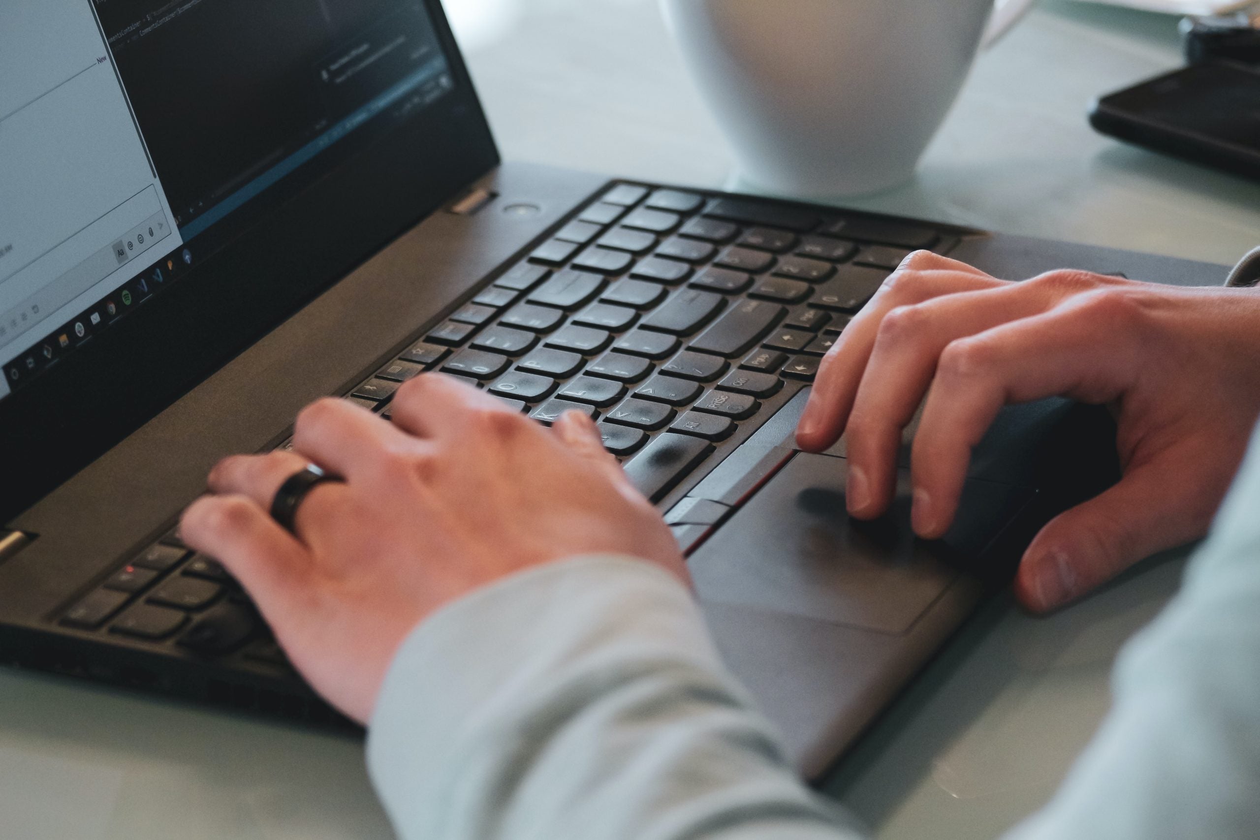 person in white long sleeve shirt using black and gray laptop computer